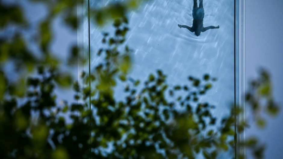 A person swims in the Sky Pool, a transparent acrylic swimming pool bridge in London, as the Met Office reports the UK has had its sunniest spring since records began with 630 hours of sunshine between March 1 and May 27