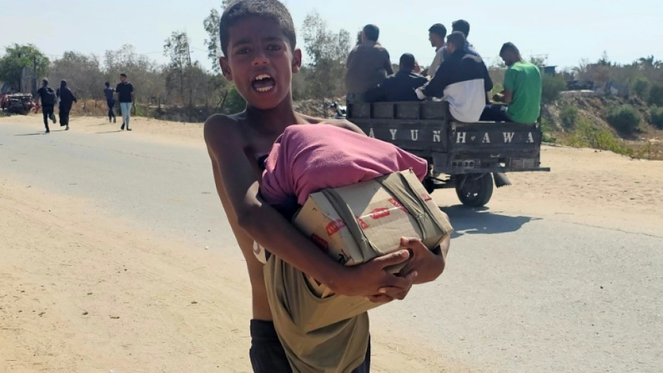 A boy walks with humanitarian aid relief packages as displaced Palestinians receive aid from a US-backed foundation in Rafah in southern Gaza