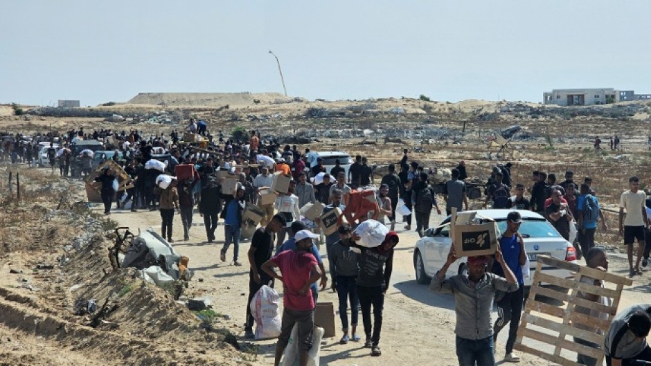 Displaced Palestinians walk along a road to receive humanitarian aid packages from a US-backed foundation in Rafah