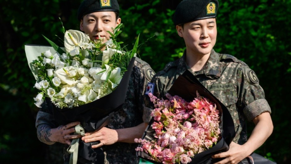 (L-R) Jungkook and Jimin of K-pop supergroup BTS hold bouquets of flowers shortly after their release from 18 months of South Korean military service
