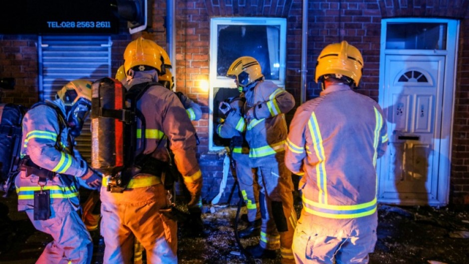 Firefighters arrive at a house that was attacked by protestors during the second night of riots targeting foreigners in Ballymena, Northern Ireland