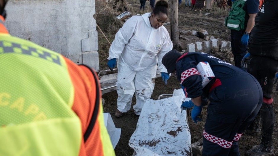 Forensics personnel write on a body bag after finding victims of the flooding near Mthatha as the death toll hit at least 78
