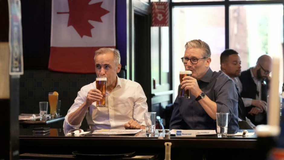 British Prime Minister Keir Starmer (R) and Canadian Prime Minister Mark Carney have a beer at the Royal Oak pub in Ottawa before they head to the Group of Seven summit