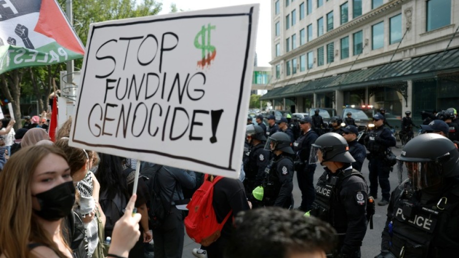 A protester holds a sign during a demonstration in front of Calgary City Hall on June 15, 2025, as world leaders converge in Canada for the G7 Summit
