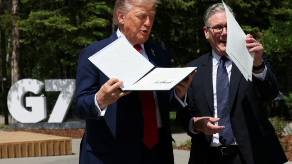 US President Donald Trump holds a signed US-UK trade deal next to British Prime Minister Keir Starmer