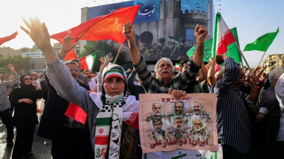 Iranians wave flags and placards during a rally protesting the US attack on Iran in Enghelab Square in Tehran