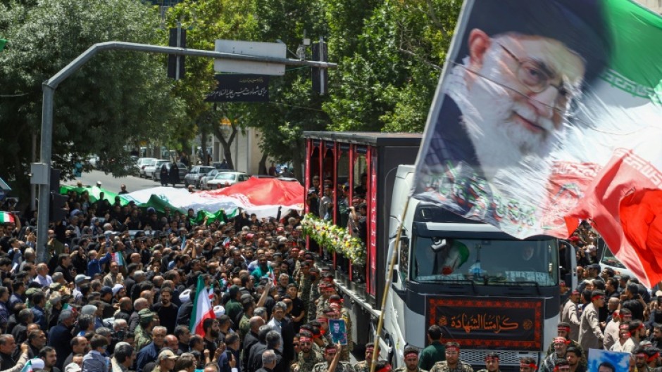 A woman holds a portrait of slain Iranian Revolutionary Guards commander Hossein Salami as mourners attend his funeral and that of other military commanders killed during Israeli strikes