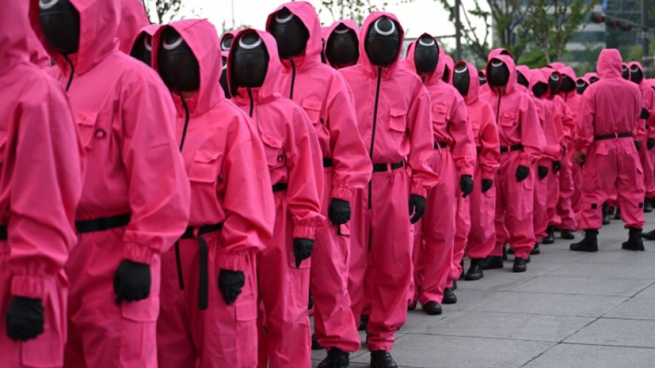 Fans gathered near Seoul's Gyeongbokgung Palace, led by marchers dressed in the bright pink uniforms worn by the show's mysterious masked agents