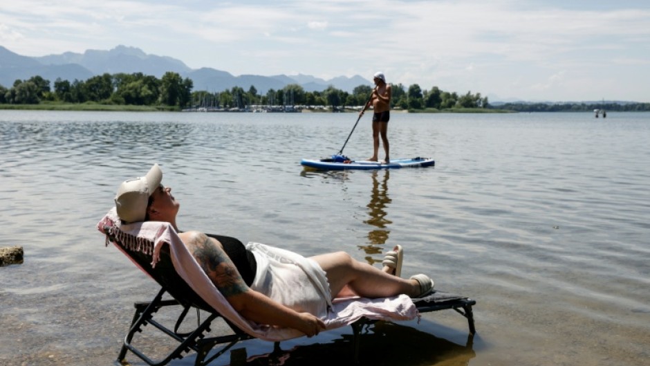 A woman puts her deck chair in the water at a beach at the Bavarian lake Chiemsee, where temperatures reaches some 32 degrees celsius on July 2, 2025