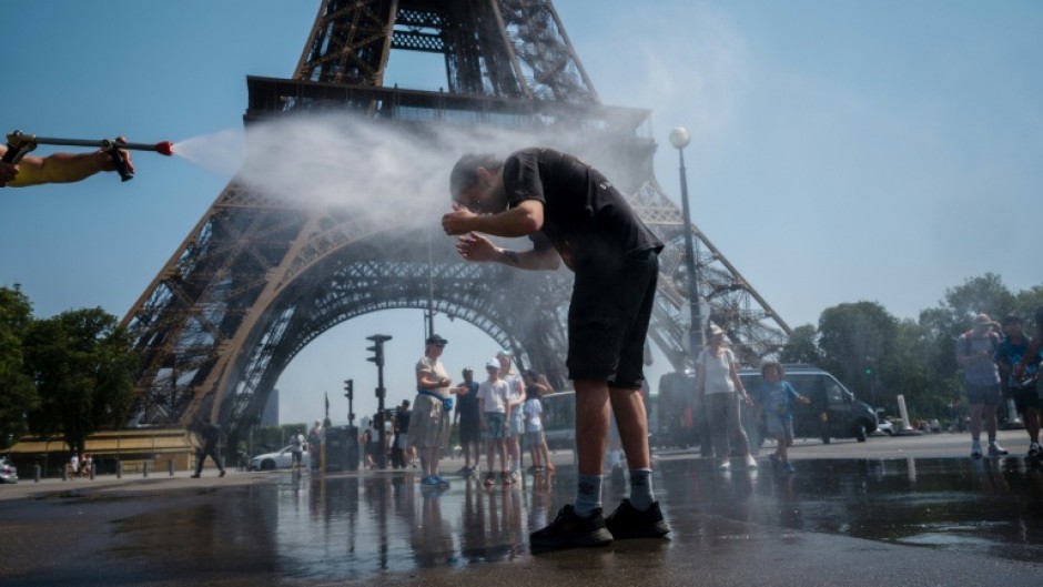 A municipal employee sprays water to cool off tourists in front of the Eiffel Tower in Paris, on July 2, 2025, as a heatwave hits France