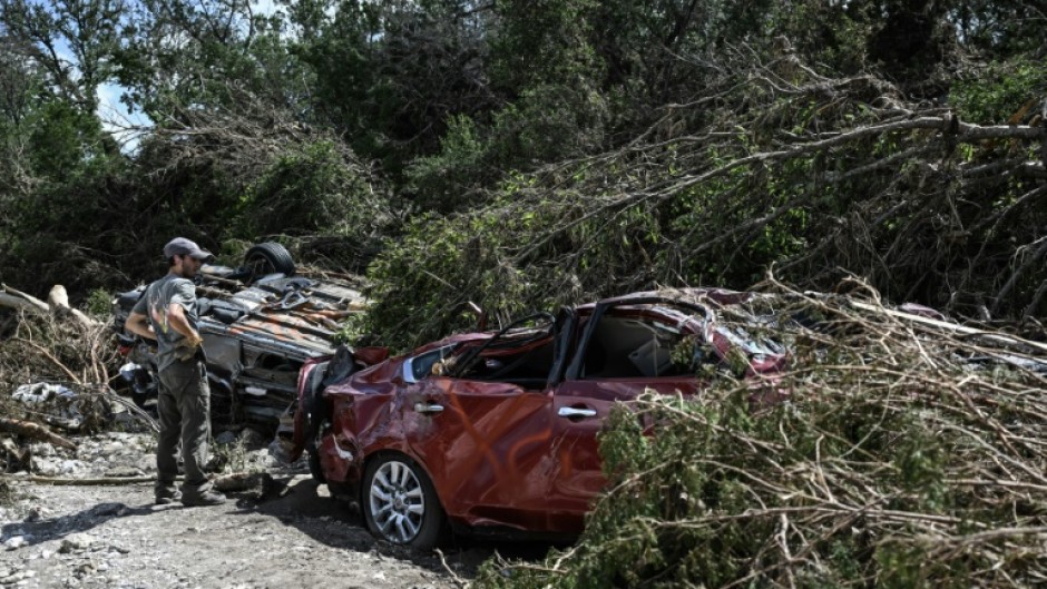 A man searches for missing people by a crushed car near the Guadalupe River in Hunt, Texas