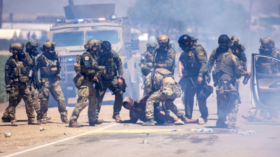 US Customs and Border Protection officers make an arrest after pulling a person out of their vehicle outside an immigation raid at Glass House Farms in Camarillo, California