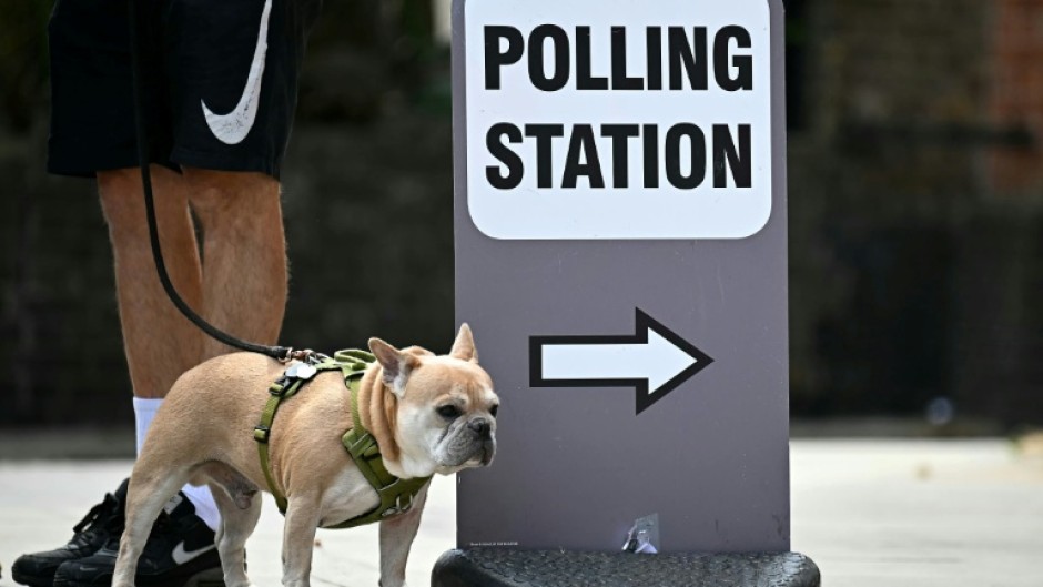 A dog stands by a polling station sign in Hackney, east London, on July 4, 2024 when Britain held its last general elections