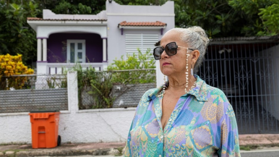 Gloria Cuevas poses in front of her former house in Rincon, Puerto Rico, which has been converted into an Airbnb