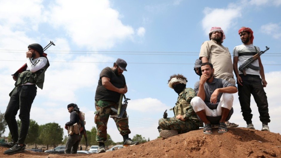 Tribal fighters stand next to a government checkpoint east of Sweida city, in southern Syria