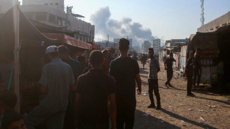 Displaced Gazans look on as smoke billows over the southern city of Khan Yunis following Israeli strikes.