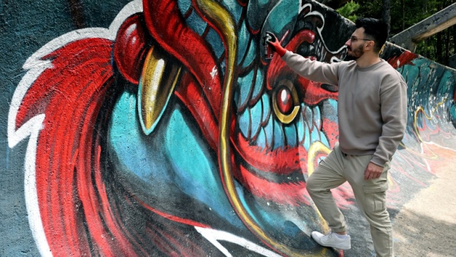 Street artist Kerim Musanovic puts the finishing touches to touches to a painting on the former Olympic bobsled track at Mount Trebevic, near Sarajevo