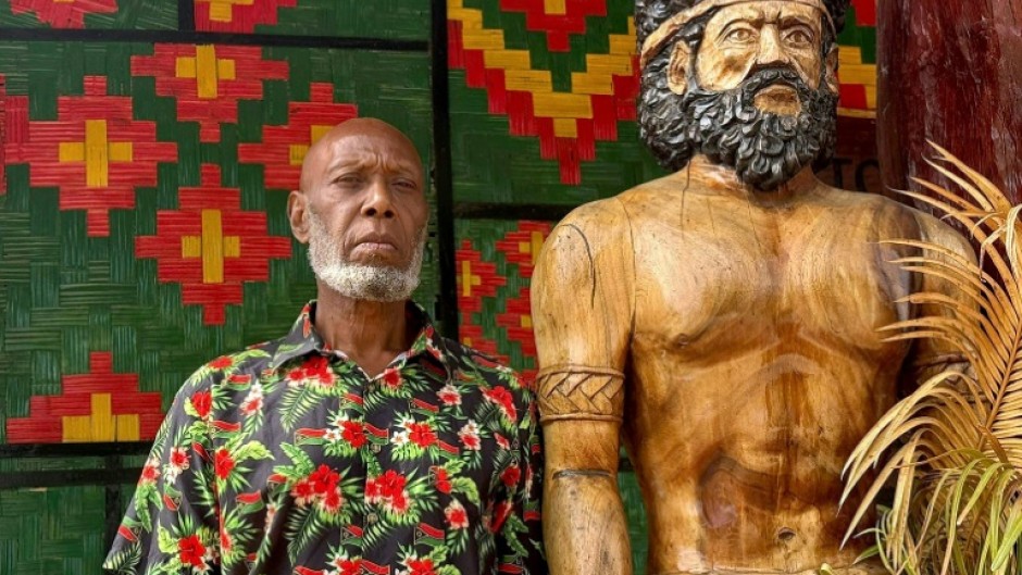 Head chief of the volcanic island of Ambrym, George Bumseng, stands next to a wooden statue in the Vanuatu capital of Port Vila on July 24, 2025