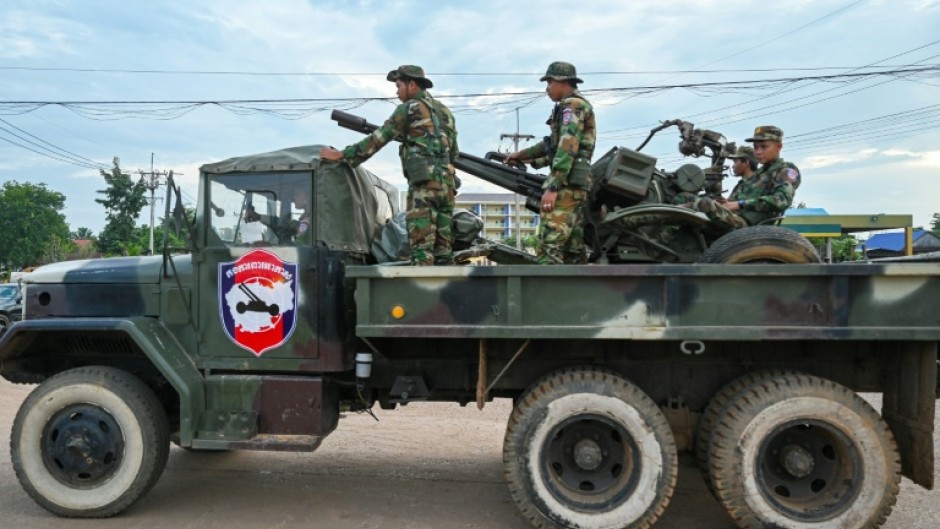 Cambodian soldiers stand on a military truck with an anti-aircraft gun in Oddar Meanchey province