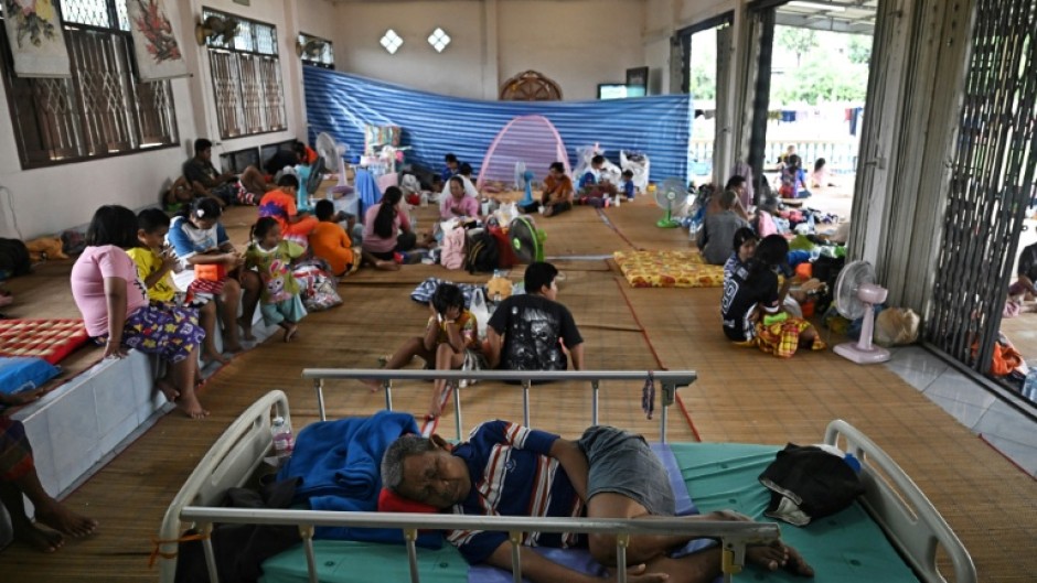 Evacuees displaced by the ongoing conflict between Thailand and Cambodia rest at a makeshift evacuation center inside a Buddhist temple in Thailand's Si Sa Ket province