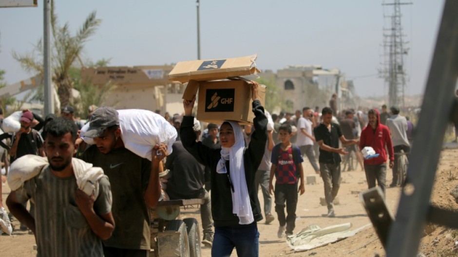 A Palestinian woman carries a food parcel from a US-backed Gaza Humanitarian Foundation distribution point in the central Gaza Strip