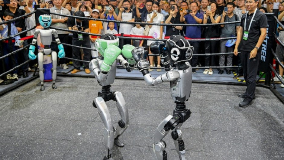 People watch humanoid robots boxing at an exhibition during the World AI Conference in Shanghai