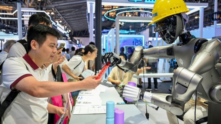 People watch a robot performing tasks at an exhibition during the World AI Conference in Shanghai