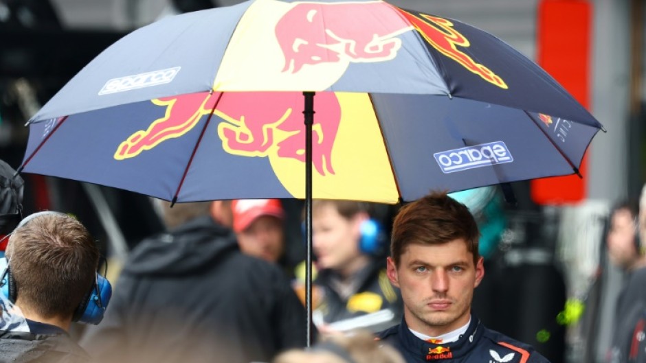 Max Verstappen takes refuge under an umbrella as rain delayed Belgian Grand Prix start