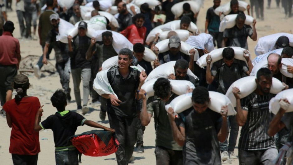 Palestinians carrying sacks of flour after trucks carrying humanitarian aid entered northern Gaza