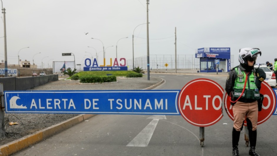 A Peruvian traffic police officer sets up a roadblock during a tsunami warning in La Punta, Callao province