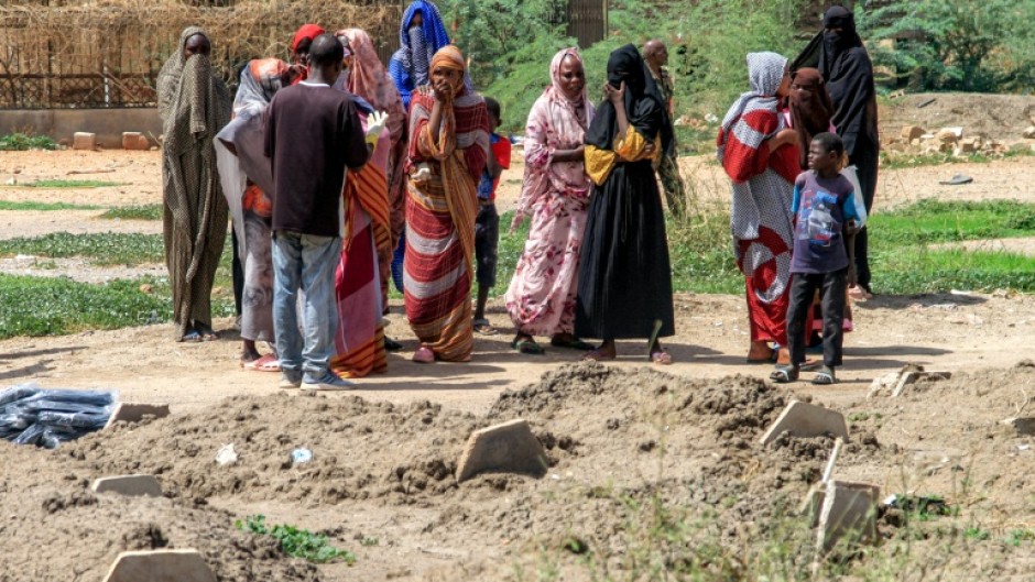 Bereaved relatives gather by the makeshift graves, waiting for the chance to give their loved ones a proper burial