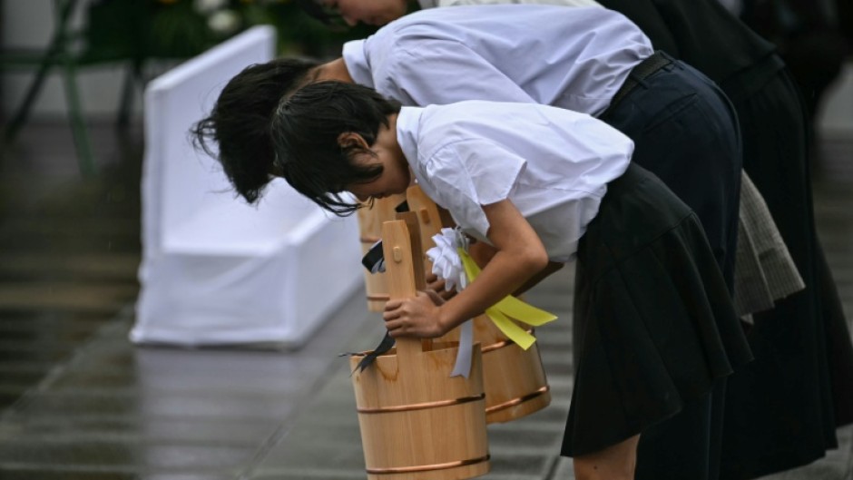 Schoolchildren make a ceremonial water offering during a memorial event marking the 80th anniversary of the US atomic bombing of Nagasaki