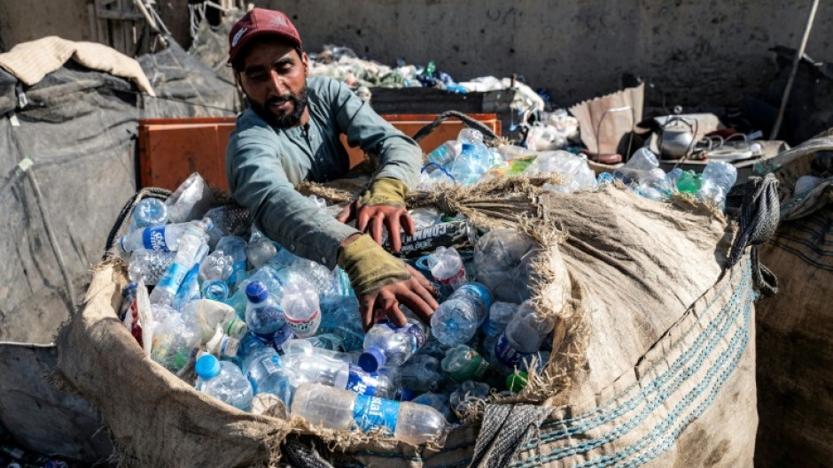 An Afghan worker loads plastic bottles into a sack at a recycling yard in Kabul