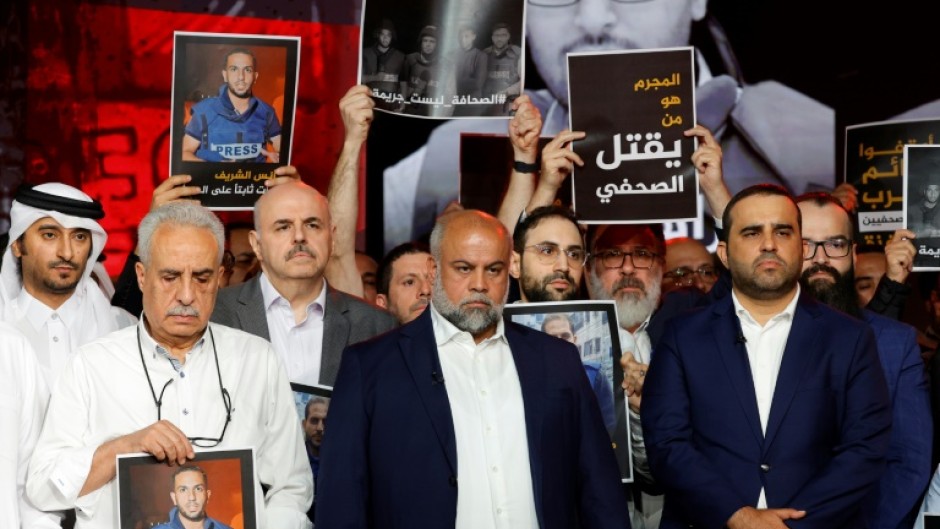 Wael Al-Dahdouh, Al Jazeera's Gaza bureau chief, stands with anchor and presenter Mohamed Krichen and presenter Tamer Almisshal during a moment of silence to honour five of their colleagues killed in an overnight Israeli strike in Gaza City