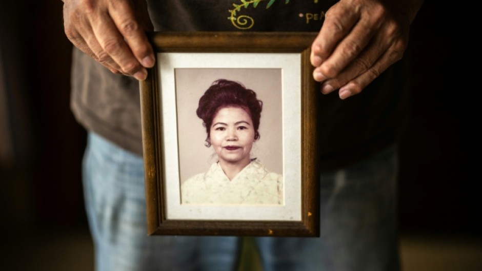 This photo taken on June 8, 2025 shows Takemasa Kinjo, who was a high school student when his mother was killed by a US Marine in 1974, holding her portrait during an interview with AFP