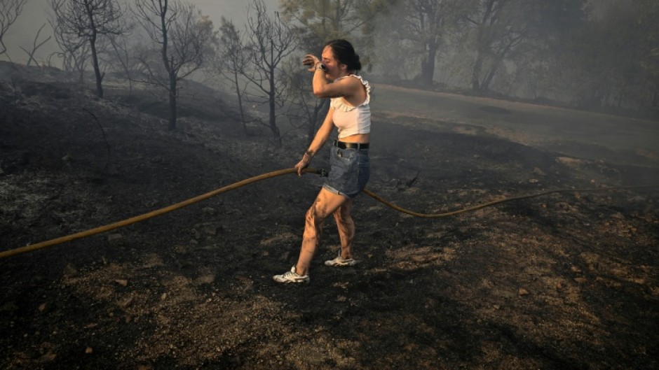 A woman tries to extinguish a wildfire near the village of Larouco in northwestern Spain on August 13, 2025