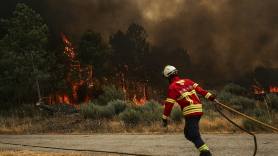 Firefighters try to extinguish a wildfire at Casal do Monte village in Trancoso, Portugal on August 13, 2025