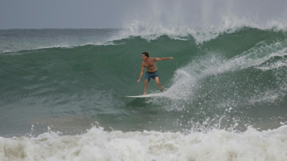 A surfer rides a wave at La Pared beach as Hurricane Erin approaches in Luquillo, Puerto Rico