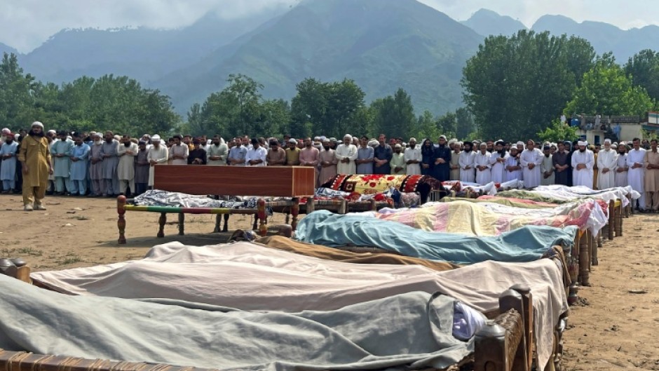 Mourners gather for mass funerals, where bodies wrapped in shawls were laid out on the village ground