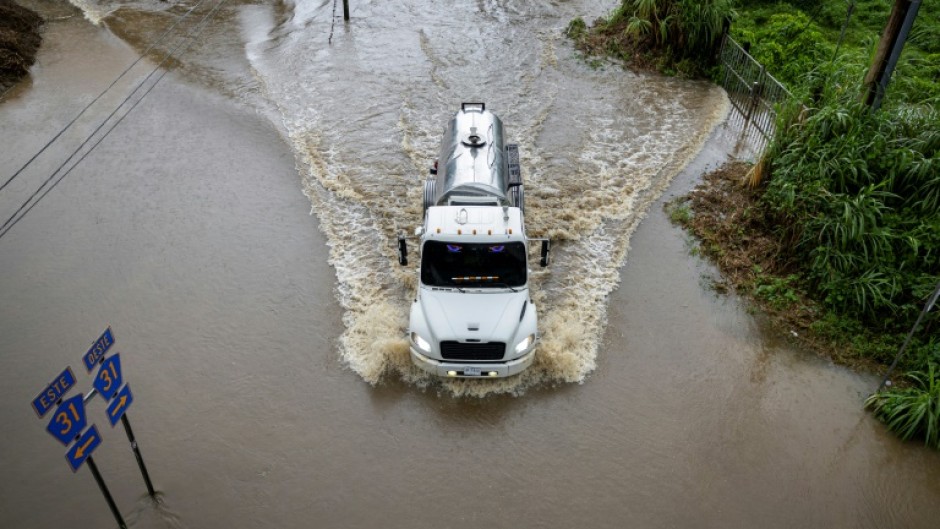 A truck drives through a road in Naguabo, Puerto Rico that was hit by flooding from Hurricane Erin