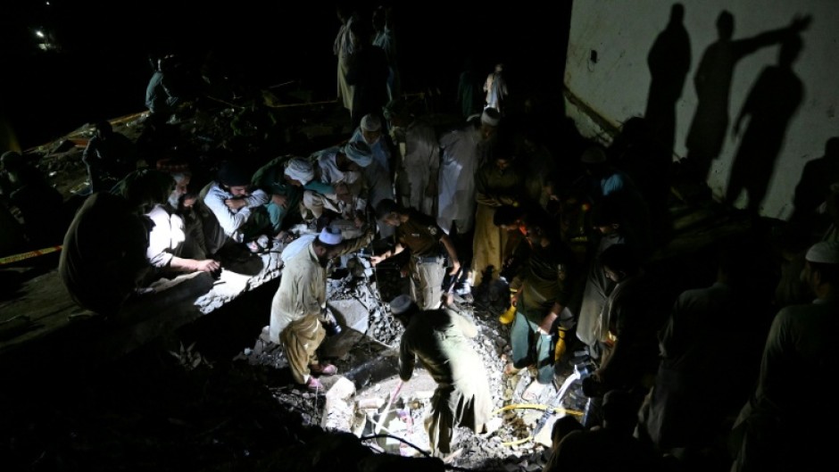 Rescue workers and residents search for victims in the debris of collapsed houses after a cloudburst in Dolari village, in northern Pakistan