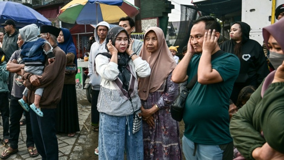People cover their ears as a truck mounted with a tower of subwoofers drives past during a "sound horeg", which loosely means to move or vibrate in Javanese