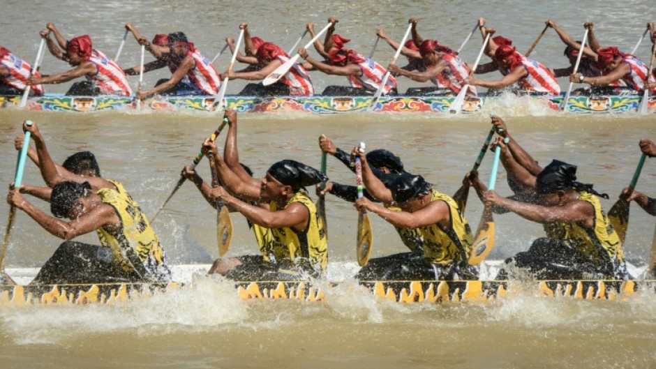 Participants paddle hard on their boat during the race held on the Kuantan River