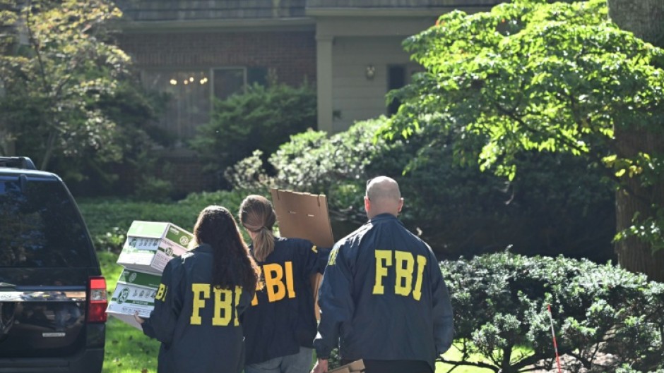 FBI agents carry boxes as they arrive at the house of John Bolton, President Donald Trump's former national security adviser