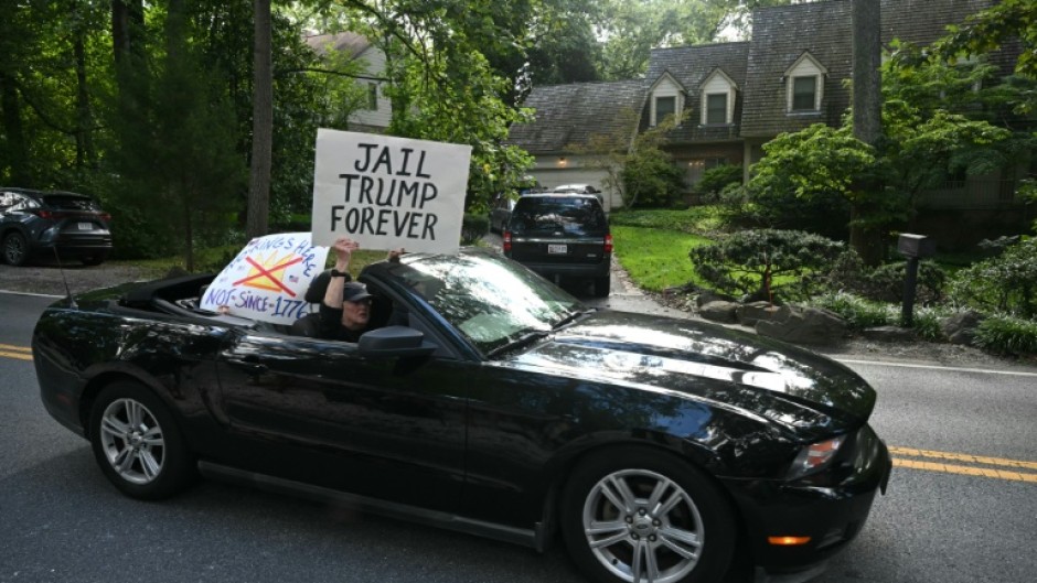 Protestors holding signs drive past the home of John Bolton, President Donald Trump's former national security adviser