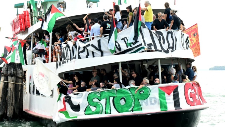 People aboard a boat wave Palestinian flags as they arrive to take part in a demonstration in support of Gaza at the Venice Lido