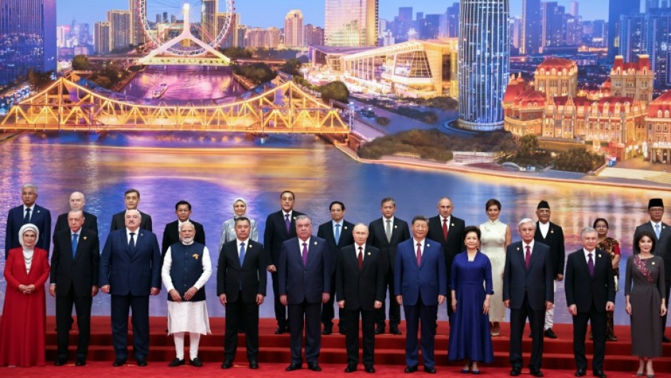 In this photograph distributed by the Russian state agency Sputnik, Russia's President Vladimir Putin, Chinese President Xi Jinping, his wife and foreign leaders pose during the Shanghai Cooperation Organization (SCO) Summit