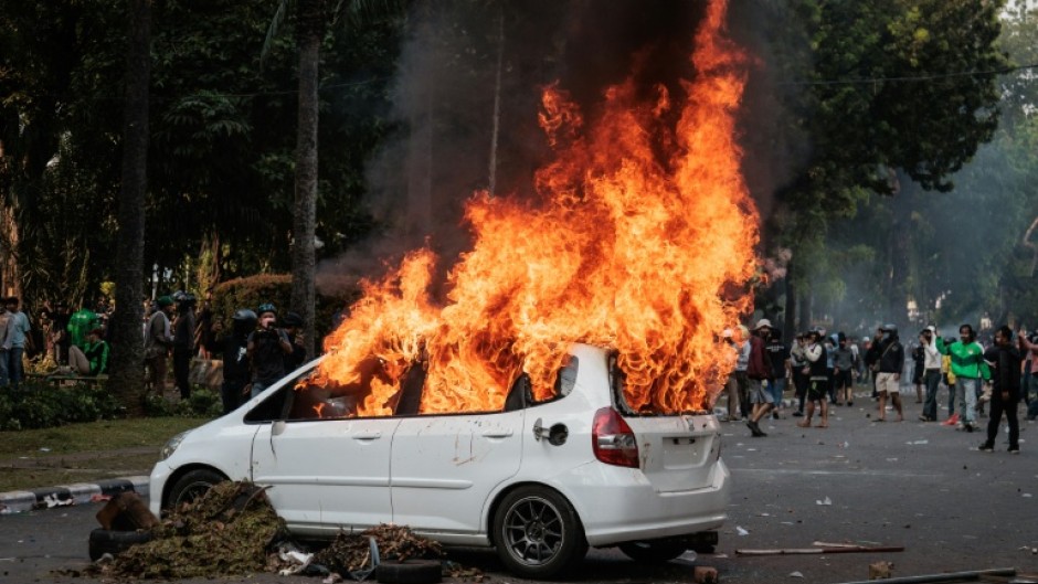 A car burns after being set ablaze during a protest against the Mobile Brigade Corps, or 'Brimob' in Jakarta