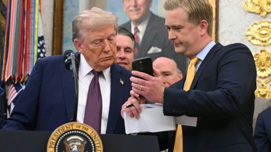 Fox News reporter Peter Doocy shows US President Donald Trump his phone during an Oval Office press conference