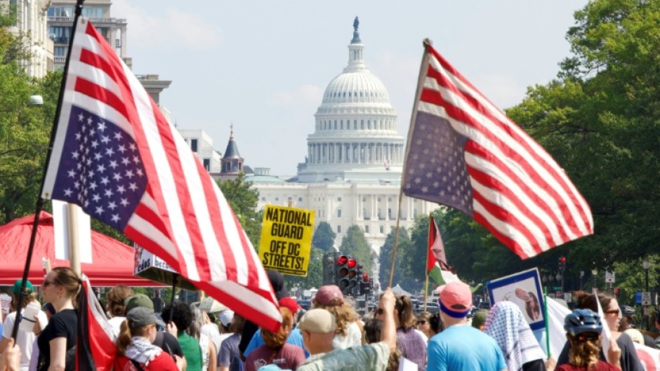 Demonstrators hold inverted US flags near the US Capitol during the "We Are All DC" national march calling for an end to the deployment of National Guard troops in Washington, DC
